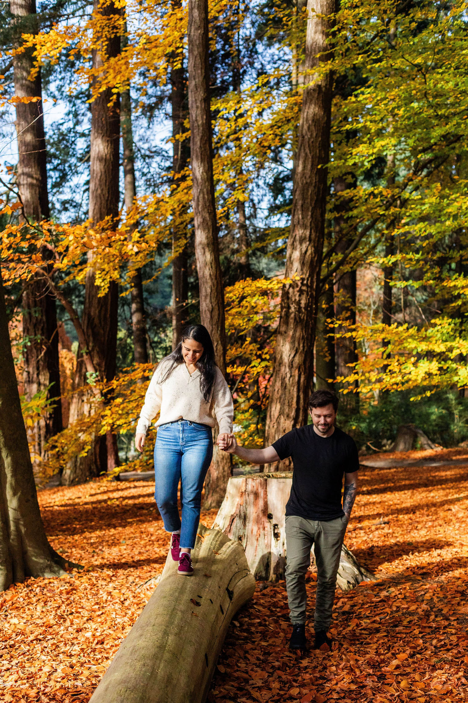 couple walking on a log at stanley park engagement session
