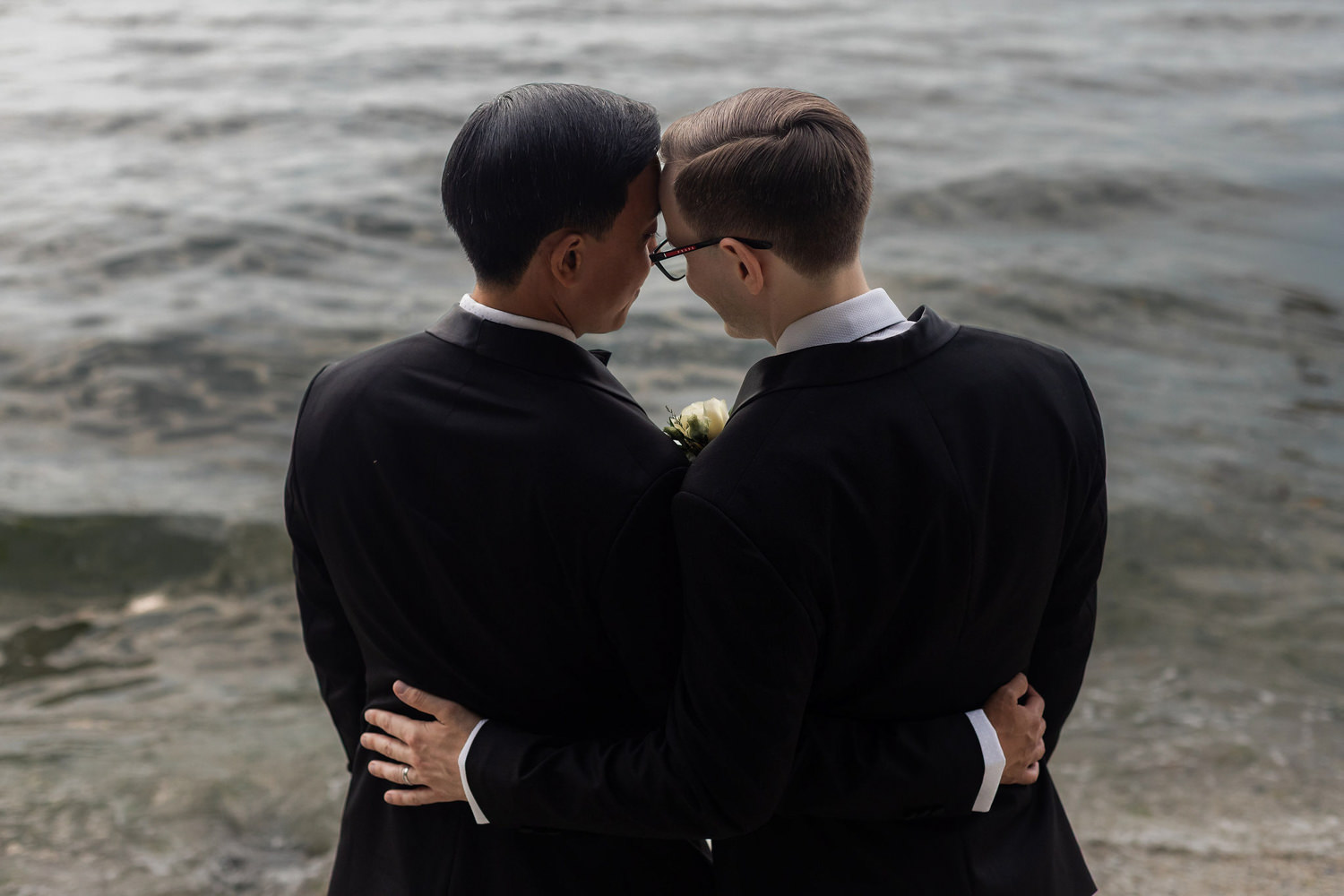 grooms touching foreheads by the water at stanley park